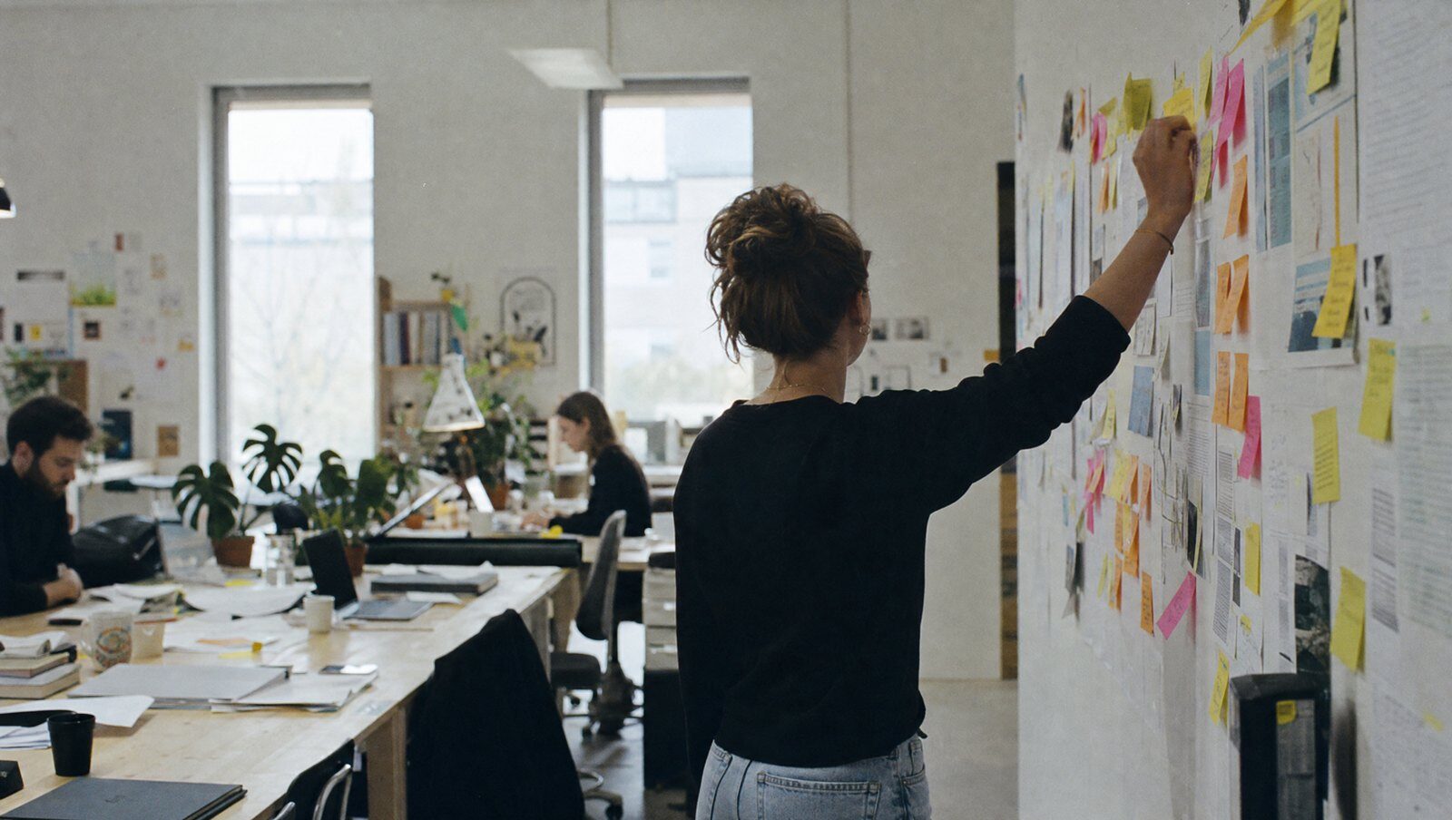 Mur de post-its colorés pendant un atelier, une main place une note